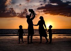 a family standing on the beach at sunset