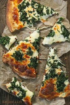 several slices of pizza with cheese and spinach on top, sitting on wax paper