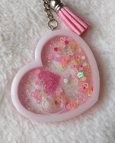 a pink heart shaped keychain with glitters and hearts on it's side