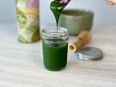 a person pouring green liquid into a jar