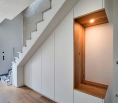 an empty room with white walls and wood flooring next to a staircase leading up to the second floor