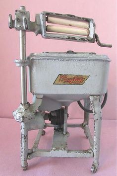 an old fashioned meat slicer sitting on top of a pink table