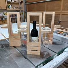 three wine glasses sitting on top of a table next to a bottle and glass holder