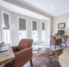 a living room with two chairs and a rug on the floor in front of windows