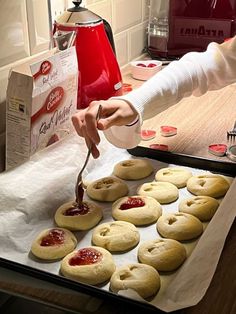 a person is spreading jam on some cookies