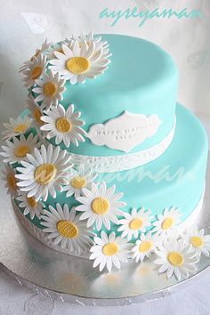 a three layer cake with daisies on top