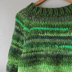 a green sweater hanging on a wooden hanger