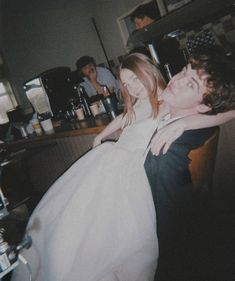 a bride and groom hugging each other in the kitchen