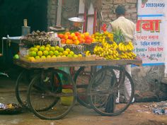 a man standing next to a cart filled with fruit