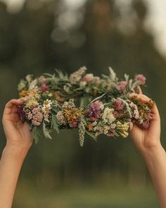 two hands holding flowers in the middle of each other's hands, with trees in the background