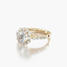 a yellow gold engagement ring with an oval cut diamond surrounded by small round brilliant diamonds