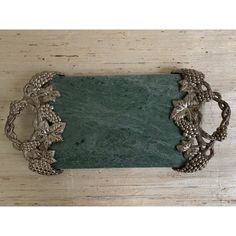 an ornate metal frame sitting on top of a wooden table next to a green stone plaque