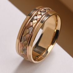 two tone gold wedding ring with an intricate design on the inside and outside, sitting on a white surface