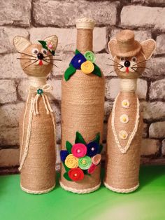 three decorated bottles sitting on top of a green table next to a brick wall,