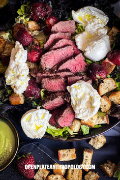 a steak salad with eggs and strawberries on the side