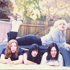 three women laying on the back of a car