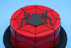 a spiderman cake with red frosting and black icing on the top, sitting on a plate