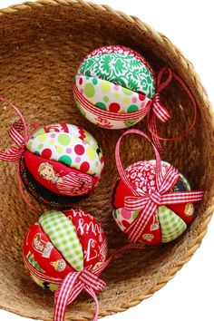 four decorated eggs in a basket with ribbons