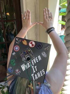 a woman wearing a graduation cap with stickers on it's head and hands in the air