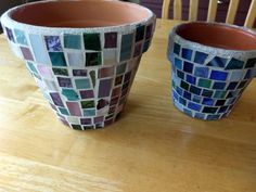 two vases sitting on top of a wooden table covered in colorful glass mosaic tiles