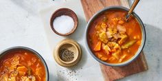 two bowls of soup on a cutting board with salt and pepper in the bowl next to them