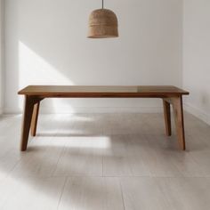 a wooden table sitting on top of a hard wood floor next to a white wall