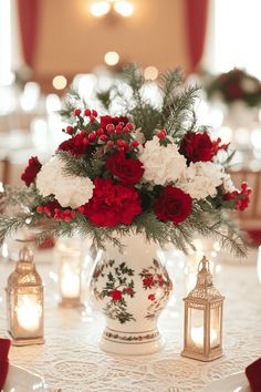 a white vase filled with red and white flowers on top of a table covered in candles