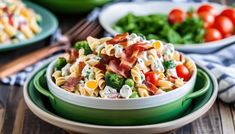 pasta salad with bacon, tomatoes and broccoli in a green bowl on a wooden table