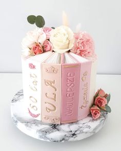 a cake decorated with books and flowers on a marble plate