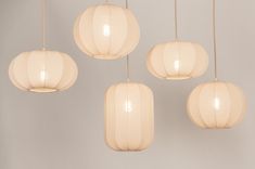 five white paper lanterns hanging from the ceiling in a room with light grey walls and flooring