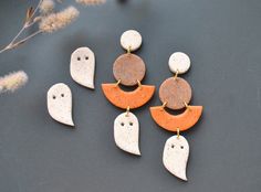 five different shapes of halloween earrings on top of a black surface with flowers in the background