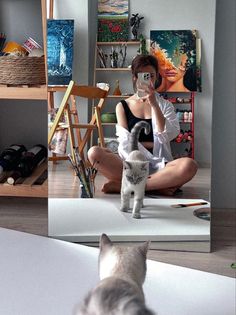 a woman sitting on the floor with a cat and taking a selfie in front of her