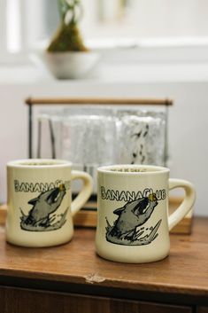 two coffee mugs sitting on top of a wooden table