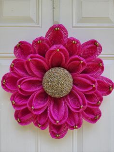 a pink flower is hanging on the front door with mesh netting and beads around it