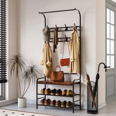 a coat rack with shoes, umbrellas and purses on it next to a potted plant