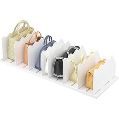 six purses are lined up on a white shelf with handles and hooks to hold them