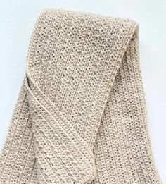 a crocheted blanket folded up on top of a white surface with the end rolled down