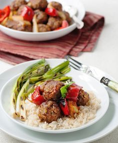 meatballs, asparagus and red peppers are served over rice on a white plate