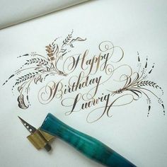 a fountain pen sitting on top of a paper with the words happy birthday being written in cursive writing