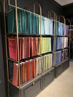 an assortment of fabrics are on display in a store window, with gold racks holding them