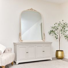 a living room with white furniture and a large mirror