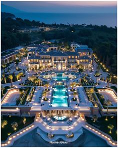 an aerial view of a mansion at night with lights on the pool and surrounding landscaping