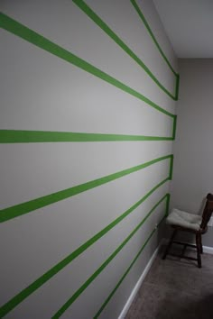 a chair sitting next to a white wall with green stripes on the walls and floor