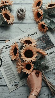 sunflowers are arranged on top of an old newspaper with scissors and twine