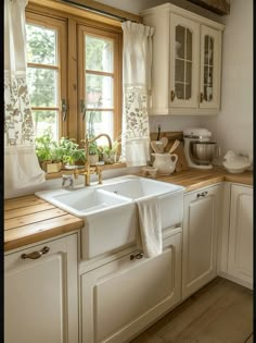 a white kitchen sink sitting under a window next to a wooden counter top with dishes on it