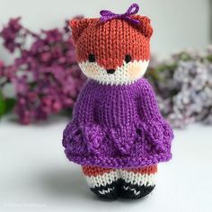 a knitted teddy bear wearing a purple dress