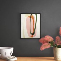 a vase filled with pink flowers sitting next to a painting on a wall above a wooden table