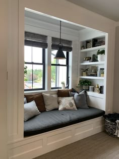 a window seat in the corner of a living room with pillows and other items on it