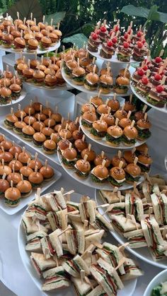 many sandwiches are arranged on trays with toothpicks