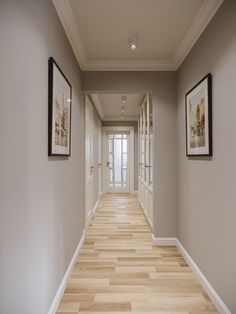 an empty hallway with two framed pictures on the wall